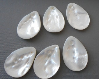 May include: Six white iridescent mother of pearl teardrop shaped pendants with a hole at the top for stringing.