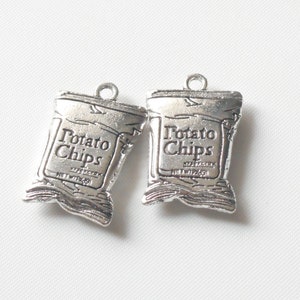 May include: Two silver charm pendants shaped like potato chip bags. Each bag has the text "Potato Chips" printed on it.