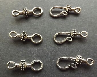 May include: Six silver-toned metal clasps for jewelry making. Three clasps are round with a beaded design and a loop on each side. The other three clasps are hook-shaped with a beaded design.