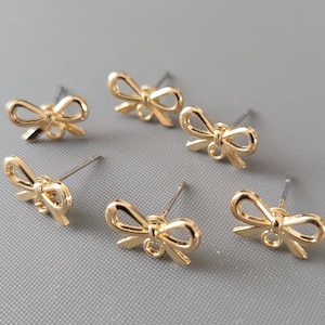 May include: Six pairs of gold bow-shaped earrings with a post back.