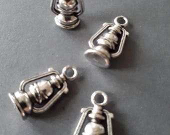 May include: Four silver-toned metal lantern charms with a loop for hanging. The lanterns have a detailed design and are perfect for adding a rustic touch to jewelry or crafts.