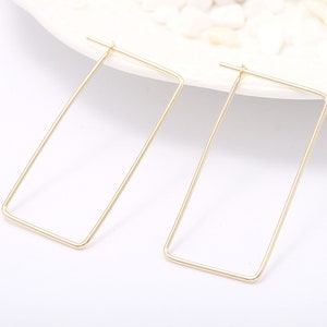 May include: A pair of gold-toned rectangular hoop earrings. The earrings are simple and minimalist in design.