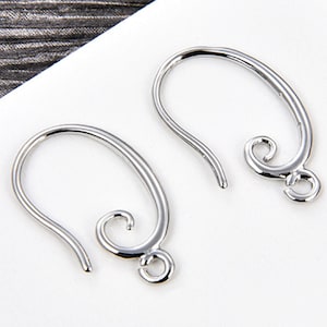 May include: Two silver-colored earring hooks. Each hook has a curved design with a looped end and a decorative swirl. The hooks are designed for jewelry making and are displayed against a white background.