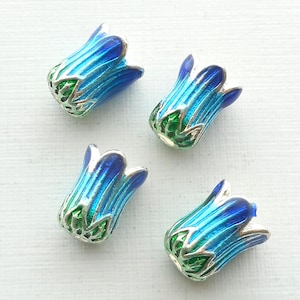 May include: Four blue and green enamel flower-shaped beads with silver accents. The beads are approximately 1 inch in length.