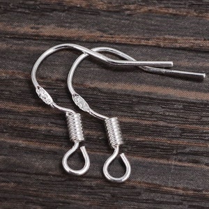 Peut inclure: Deux crochets d'oreille argentés avec une fermeture à ressort. Les crochets sont en métal et ont une finition brillante.