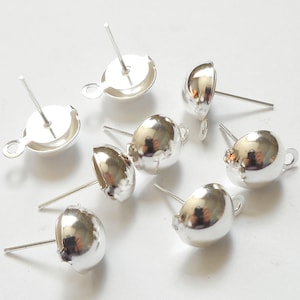 May include: A collection of silver-colored earring components. The components include a post with a flat, round base and a small loop, and a rounded, cup-shaped component with a post. The components are reflective and appear to be made of metal.