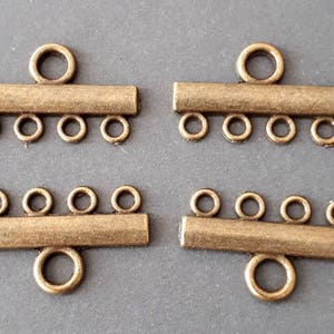 Peut inclure: Quatre fermoirs coulissants en métal doré antique avec cinq boucles chacun. Les fermoirs sont conçus pour être utilisés pour la fabrication de bijoux.