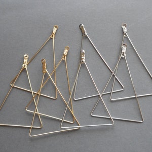 May include: Five triangle-shaped metal earring blanks, two gold and three silver, with jump rings at the top.
