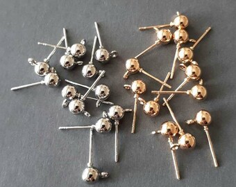 May include: A collection of earring findings with silver and gold-toned ball tops. The findings are made of metal and have a loop at the top for attaching earrings.