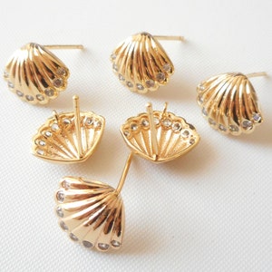 May include: Five gold-tone seashell-shaped earrings with clear rhinestones. The earrings are designed to be worn as studs.