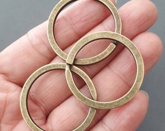Könnte beinhalten: Drei ineinander verschlungene Schlüsselringe aus antikem Goldmetall.