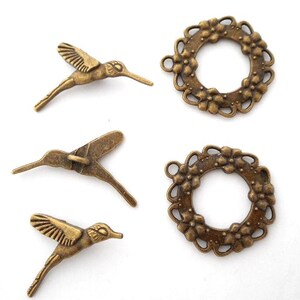 Op de afbeelding: Vier bronzen metalen bedels. Drie kolibri-bedels met gedetailleerde vleugels en snavels worden getoond. Twee bloemenkransbedels met een cirkelvormig middenstuk zijn ook te zien. Geschikt voor sieraden maken of knutselprojecten.