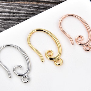 May include: Three metal earring hooks in silver, gold, and rose gold. Each hook has a curved design with a looped end for attaching earrings. The hooks are displayed on a white surface.
