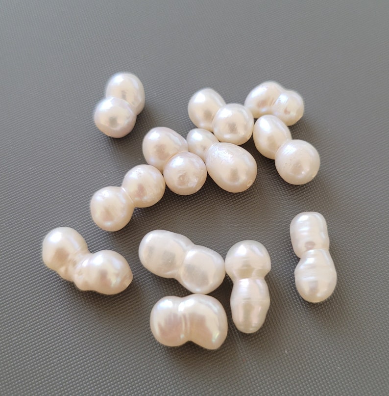 May include: A collection of off-white baroque pearl beads. The pearls are irregular in shape and have a slightly iridescent sheen.