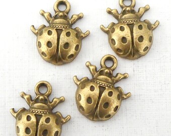 May include: Four antique gold-toned ladybug charms with black spots. Each charm has a loop at the top for attaching to jewelry or crafts.