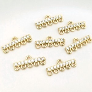 May include: Gold-coloured jewellery findings with a rectangular bar design. Each bar features a row of small, clear crystals and six loops. These findings are suitable for jewellery making and crafting projects.