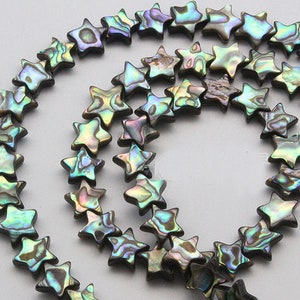 K&ouml;nnte beinhalten: Eine Str&auml;hne aus irisierenden Abalone-Muschelperlen in Sternform. Die Perlen sind in einem Mix aus Gr&uuml;n, Blau und Braun.