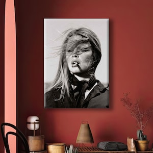 Puede incluir: Retrato en blanco y negro de una mujer con el pelo largo al viento, fumando un cigarrillo. Lleva una chaqueta oscura y una bufanda. La imagen es una impresi&oacute;n en lienzo.