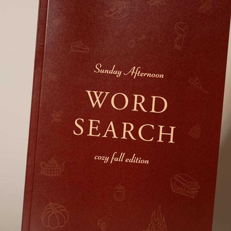 Puede incluir: Un libro de color burdeos titulado "Sunday Afternoon Word Search cozy fall edition". La portada presenta ilustraciones decorativas con tem&aacute;tica oto&ntilde;al en un tono m&aacute;s claro de burdeos.