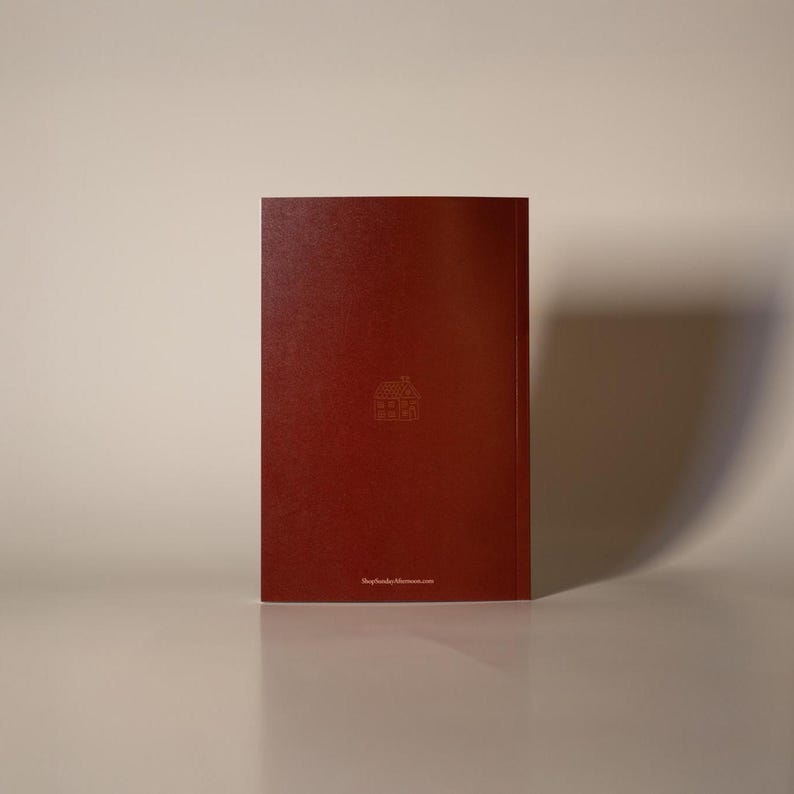 Puede incluir: Un diario de color burdeos con un icono de casa en relieve y la direcci&oacute;n del sitio web, ShopSundayAfternoon.com, en la parte inferior. El diario es rectangular y tiene un acabado liso y mate. El fondo es beige neutro.