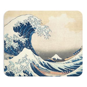 Peut inclure: Un tapis de souris rectangulaire représentant l'estampe emblématique d'une grande vague bleue déferlante avec de l'écume blanche, plusieurs bateaux en bois avec des personnes naviguant sur l'eau agitée et le mont Fuji enneigé au loin.