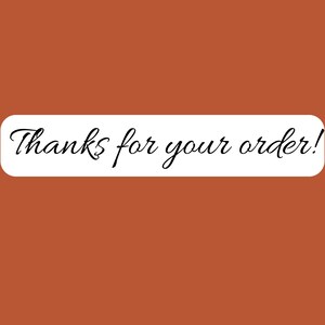 May include: A rectangular white banner with rounded corners displays the handwritten text "Thanks for your order!" in black cursive script. The banner is set against a solid, warm brown background.