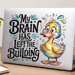 May include: A laptop decal featuring a cartoon duck with wide eyes and colourful feathers. The text reads, My Brain Has Left The Building, in bold black lettering. The design includes blue and yellow accents, stars, and water-like splashes.