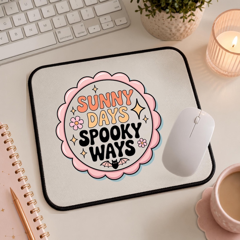 May include: A rectangular mouse pad with a black border and a central scalloped circular graphic. The graphic features the text "SUNNY DAYS SPOOKY WAYS" in orange, yellow, and black, surrounded by small pink flowers, yellow stars, and a black bat.