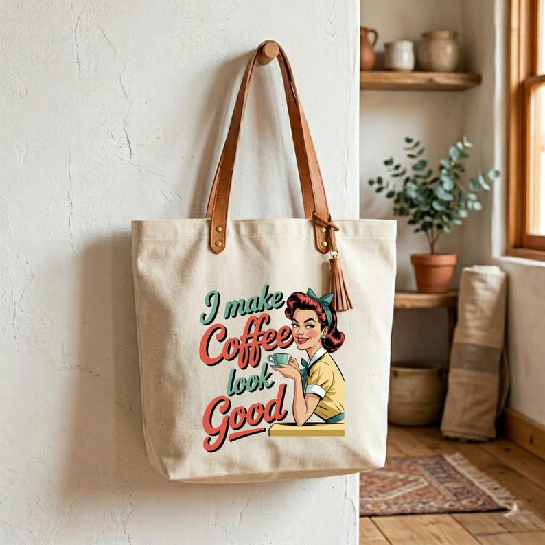 May include: Cream-colored tote bag with brown leather handles and a tassel. The bag features a retro illustration of a woman holding a coffee cup, with the text "I make Coffee look Good" in teal and red.