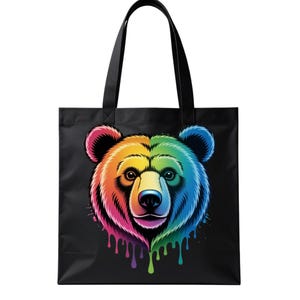 May include: Black tote bag featuring a colorful bear face design. The bear's head is split into rainbow colors, with dripping paint effects. The bag has black handles for carrying.