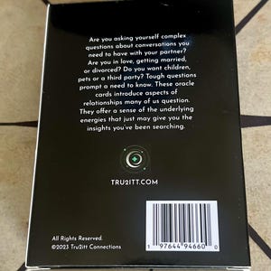 May include: A black box of oracle cards with white text. The text asks complex questions about relationships and includes the website TRU2ITT.COM. The box also has a barcode and the copyright information for 2023 Tru2itt Connections.