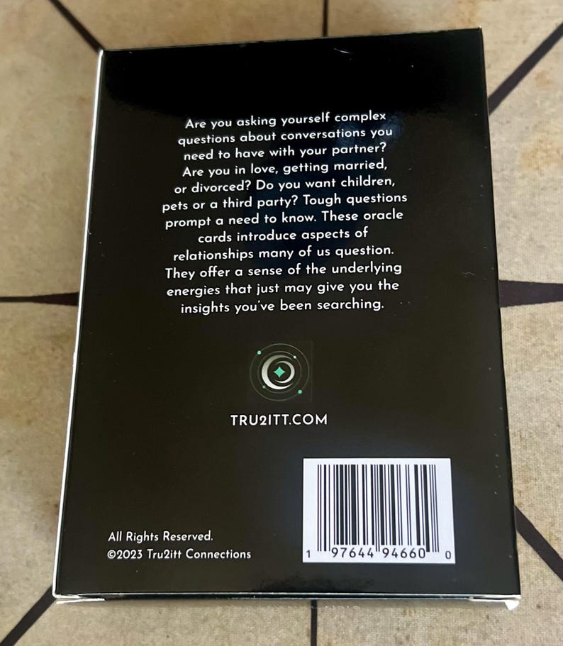 May include: A black box of oracle cards with white text. The text asks complex questions about relationships and includes the website TRU2ITT.COM. The box also has a barcode and the copyright information for 2023 Tru2itt Connections.