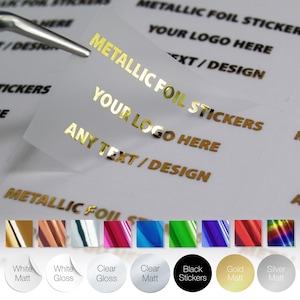 May include: Clear stickers with gold metallic foil text reading "METALLIC FOIL STICKERS", "YOUR LOGO HERE", and "ANY TEXT/DESIGN". A pair of tweezers holds a sticker. Colour options include white, clear, black, gold, and silver.