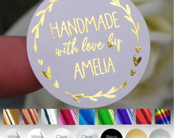 May include: A round white sticker with gold text that reads "HANDMADE with love by AMELIA." The sticker is encircled by a gold floral design and small gold hearts. Various sticker color options are shown below.