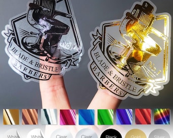 May include: Two clear stickers with a barber chair design and the text "BLADE & BRISTLE BARBERS". One sticker is silver, the other gold. Below are color options: white matt, white gloss, clear gloss, clear matt, black stickers, gold matt, and silver matt.