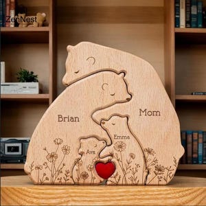 Könnte beinhalten: Holz-Bärenfamilien-Puzzle mit den eingravierten Namen "Brian", "Mom", "Emma" und "Ava". Ein rotes Herz befindet sich in der Mitte. Die Bären sind von floralen Designs umgeben. Ein dekorativer Artikel für eine Familie.