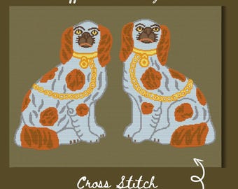 May include: A cross-stitch pattern download featuring two Staffordshire dogs. The dogs are depicted in a seated position with light blue bodies, orange and white markings, and gold-colored collars. The text "Staffordshire Dog Duo" and "Cross Stitch Pattern Download" are displayed.