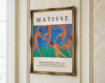 May include: A framed art print with the word "MATISSE" at the top. The print shows nude figures in a dance pose against a blue and green backdrop. The frame is ornate with a gold finish. Text at the bottom reads "BERGGRUEN & CIE 1953".