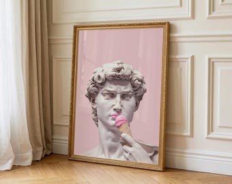 May include: A framed art print depicting a classical sculpture with pink lipstick, eating a pink ice cream cone. The background is a solid pink. The gold frame contrasts with the pink and white tones of the artwork.