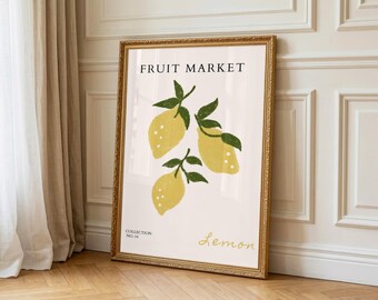 May include: A framed art print with a "Fruit Market" design, showcasing three yellow lemons with green leaves. The print includes the word "Lemon" in cursive and "Collection No. 04". The frame is gold-coloured.
