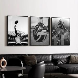 May include: A triptych of framed black and white photographs depicting American football action. One shows a player catching a football, another a helmet, and the third, players in action. The artwork is displayed above a black leather sofa.
