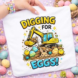 May include: White t-shirt with a yellow digger excavating for Easter eggs. The design includes a bunny, chicks, and the text "DIGGING FOR EGGS!" in yellow and blue. The image has a colourful, festive theme.