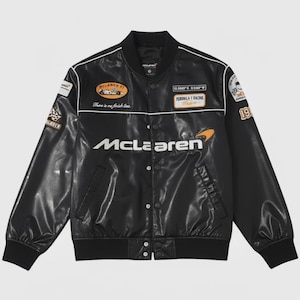 May include: Black McLaren racing jacket with white accents and multiple patches. The jacket features the McLaren logo and the text "There is no finish line." The jacket has a classic bomber style with a ribbed collar and cuffs.