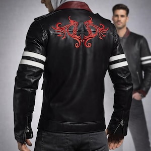 Könnte beinhalten: Schwarze Lederjacke mit rotem Stickdesign auf dem Rücken. Sie hat weiße Streifen auf den Ärmeln und einen roten Kragen. Die Jacke hat einen Reißverschluss und wird mit dunklen Jeans getragen.