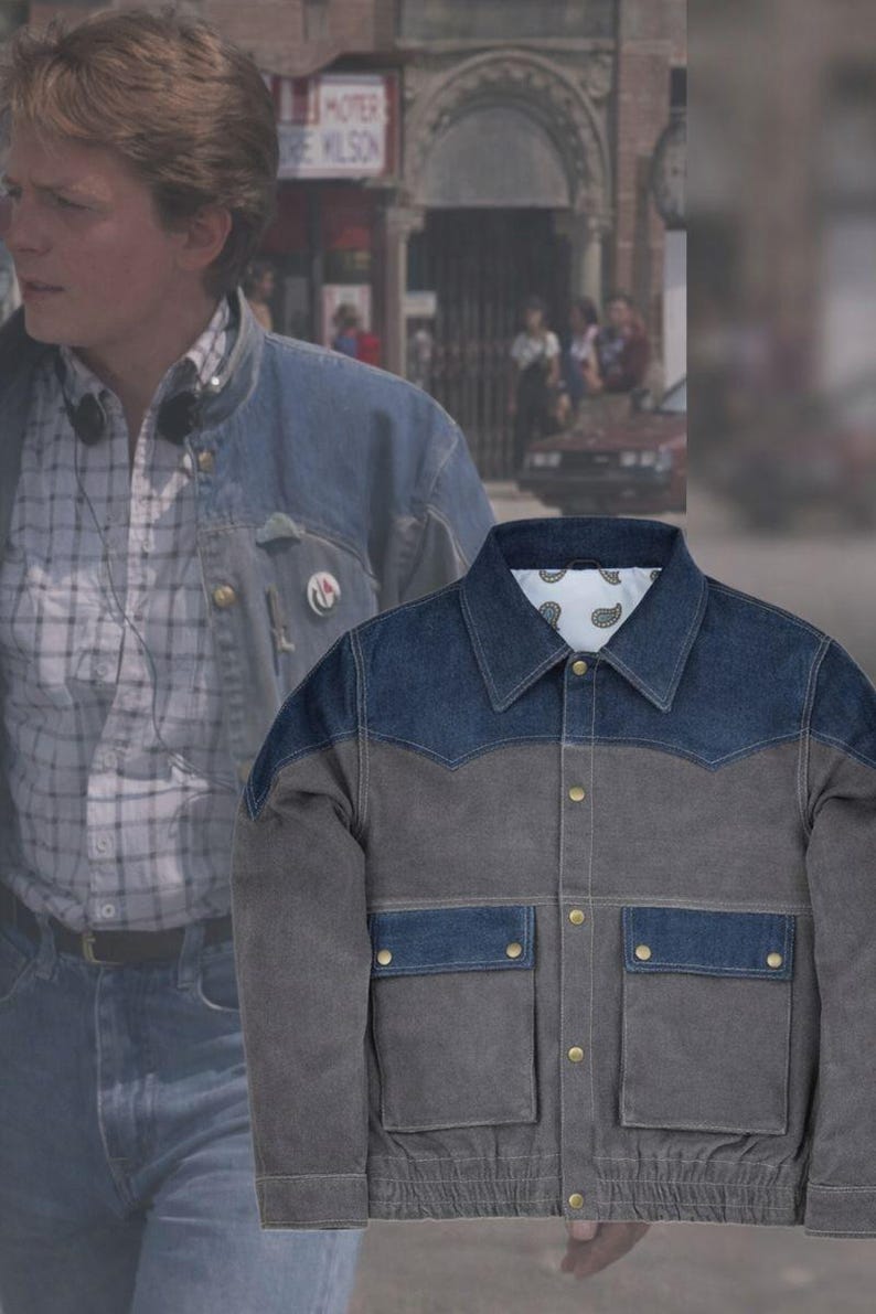 May include: A two-tone denim jacket with a blue yoke and pockets, and a gray body. The jacket has two front pockets with button closures and a button-down front. The collar is a classic style, and the jacket has a paisley lining.