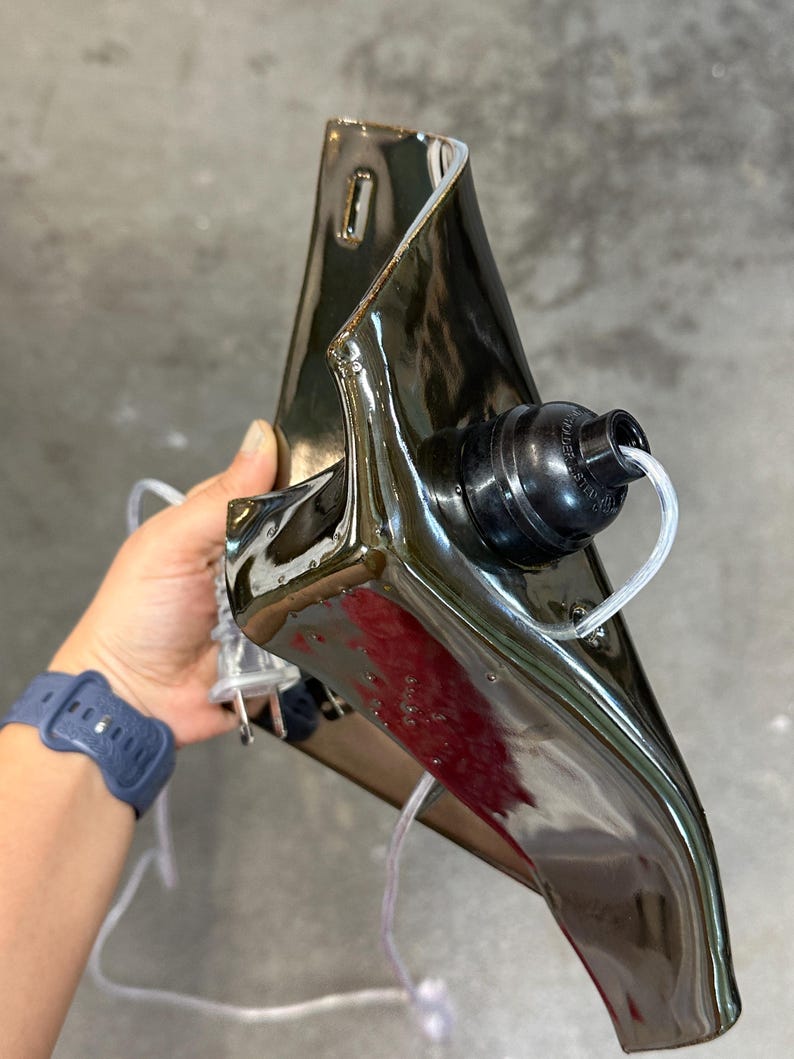 Peut inclure: Une applique murale en c&eacute;ramique brun fonc&eacute; brillant avec une forme sculpturale pli&eacute;e. Le luminaire pr&eacute;sente une douille noire circulaire mont&eacute;e sur le devant, un cordon &eacute;lectrique transparent et une fiche &agrave; deux broches. La surface est r&eacute;fl&eacute;chissante.