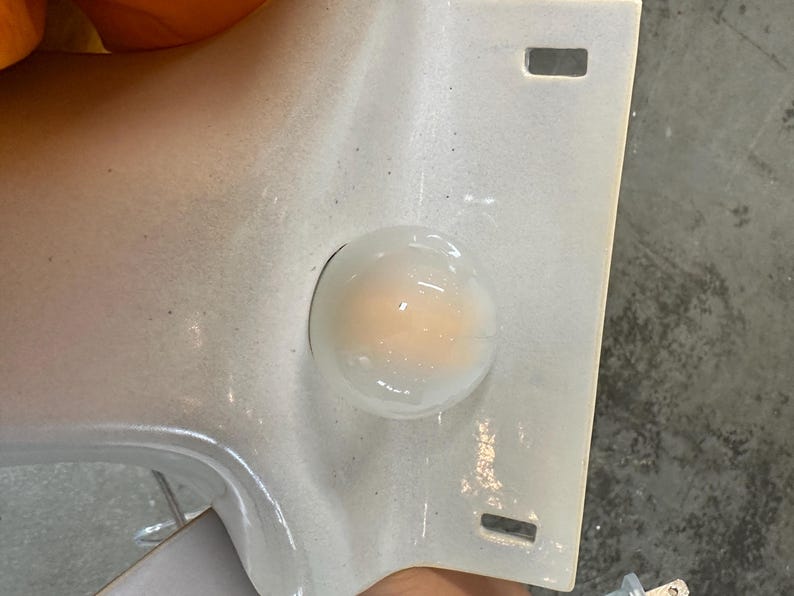 May include: A white ceramic wall plate featuring a central circular opening with a translucent, milky glass dome insert. The rectangular plate has two small, rectangular slots positioned vertically near the top and bottom edges of the surface.