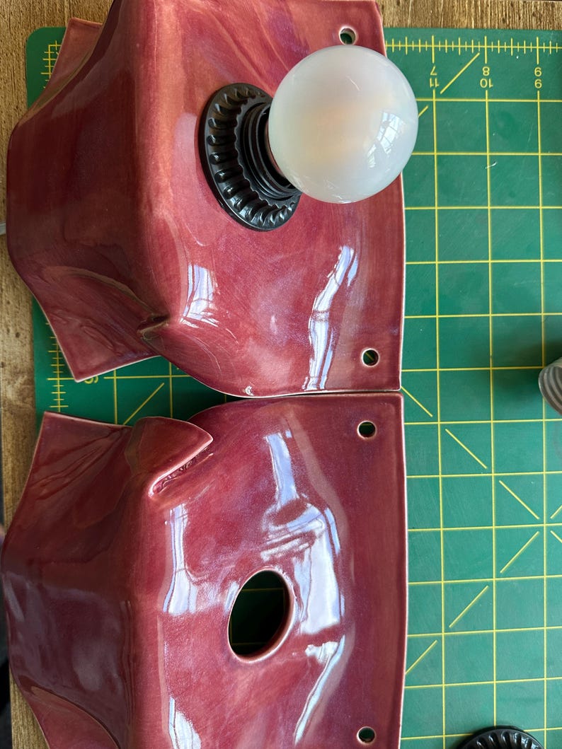 Puede incluir: Dos apliques de pared cuadrados de cer&aacute;mica en color rojo intenso brillante con bordes ondulados y plegados. Cada aplique tiene una abertura circular central para una bombilla y dos peque&ntilde;os orificios de montaje. Uno tiene una bombilla blanca.