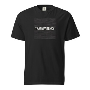 Puede incluir: Camiseta negra con la palabra "TRANSPARENCY" en blanco dentro de un cuadrado de líneas horizontales. La camiseta es de cuello redondo y manga corta.