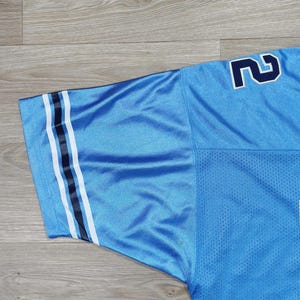 May include: Light blue mesh jersey with navy and white stripes on the sleeve. The number '2' is visible on the shoulder in navy. The jersey has a breathable, perforated texture.